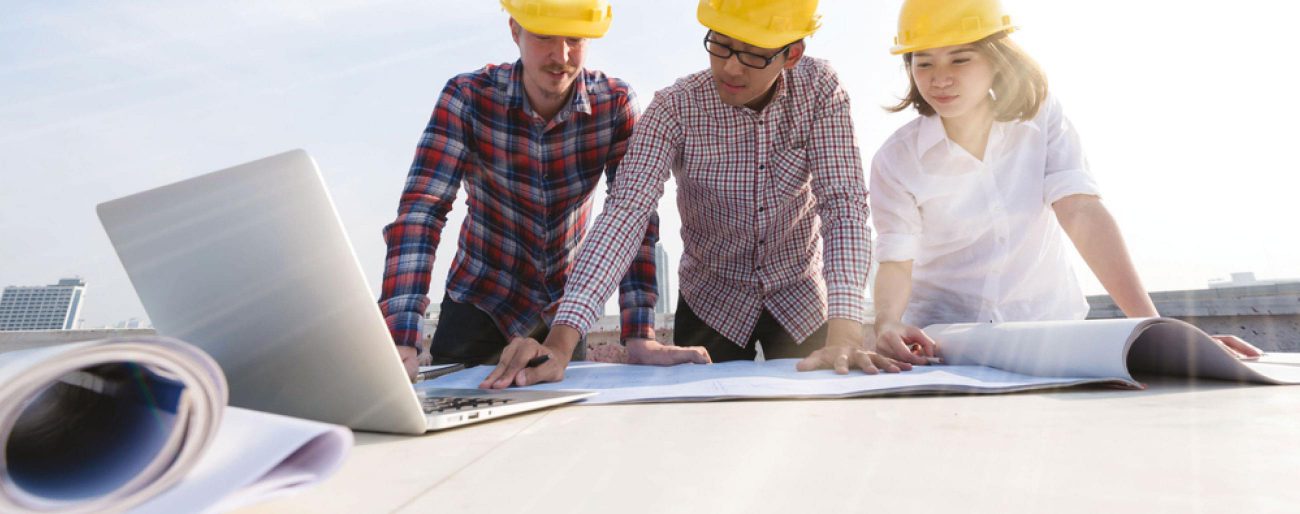 three people in hardhats looking at blueprints