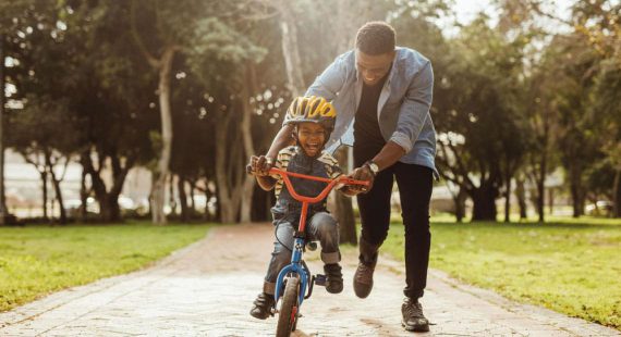 man helping young child ride a bike